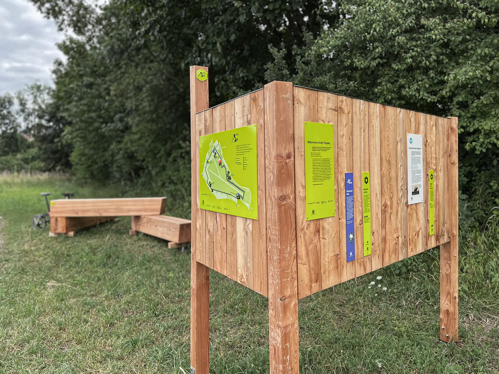 Orientierungspunkt mit Informationen zur Transformation und Sitzbank mit Veloständer im Hintergrund ©Signito GmbH