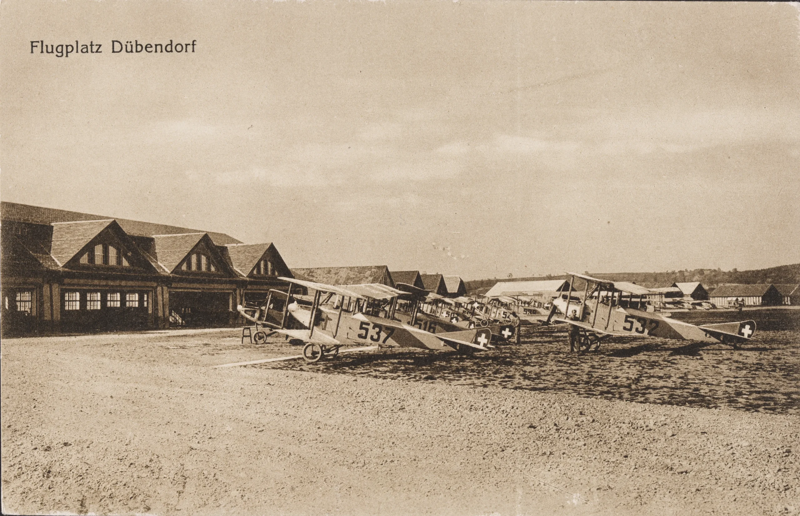 Die Halle 5 auf einer historischen Postkarte, um 1920. Vor der Halle Aufklärungsflugzeuge des Typs Häfeli DH-3. Dokumentationsstelle Luftwaffe, Dübendorf